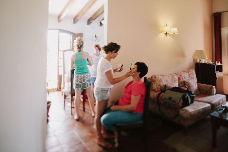 People gathered in a sunny Mediterranean-style room with exposed ceiling beams and cream walls.