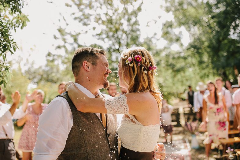 A joyful wedding celebration moment outdoors with guests blowing bubbles in a natural setting.
