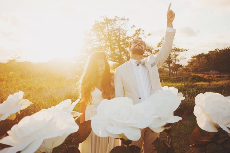 Celebratory scene with giant paper flowers and backlit sunset glow.