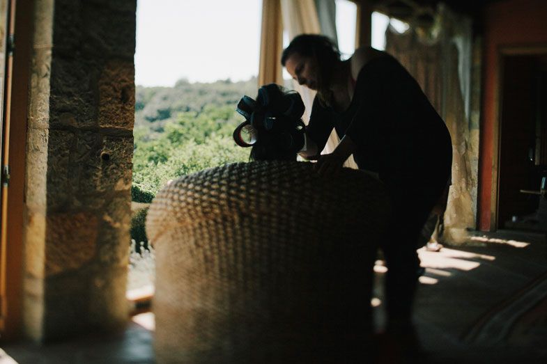 A silhouette of a photographer setting up equipment in a sunlit room.