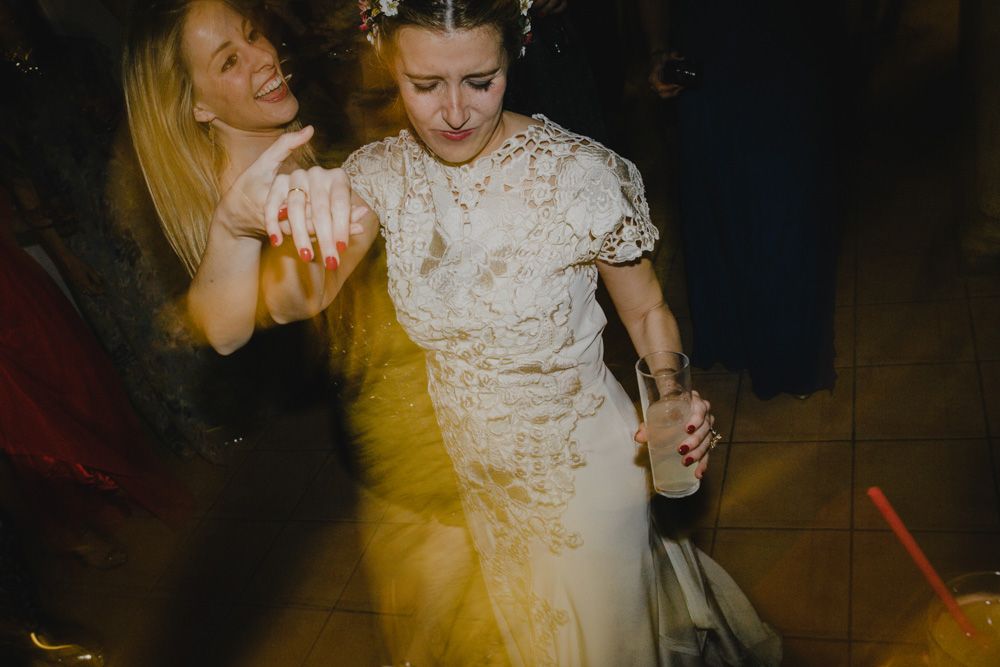 Wedding guests dancing and celebrating on a dimly lit dance floor.