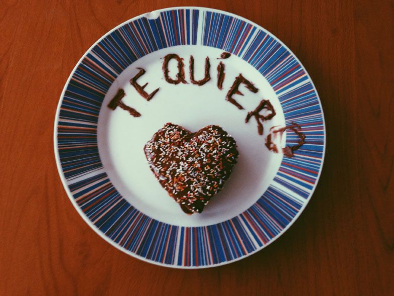 A blue striped plate with chocolate heart and 'Te Quiere' written in cocoa powder.