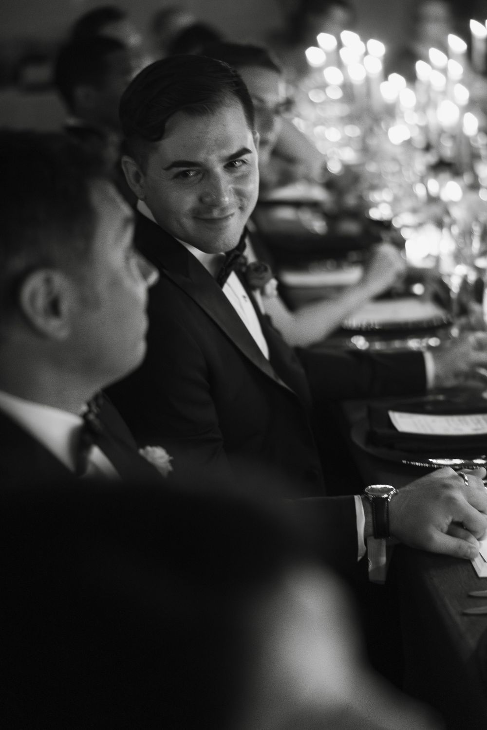 Black and white photo of elegant dinner guests at a formal wedding reception.