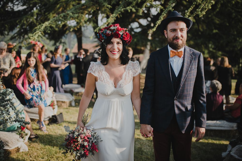 A romantic outdoor wedding ceremony with guests watching a couple walk down a grassy aisle.