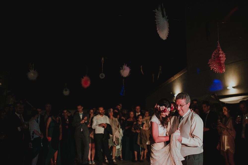 Wedding reception dance floor with hanging decorative lights and crowd in the background.