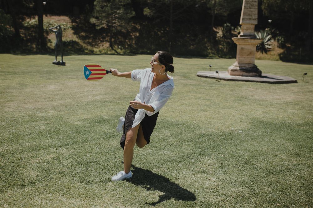 Person playing frisbee on a sunny lawn with palm trees in background.