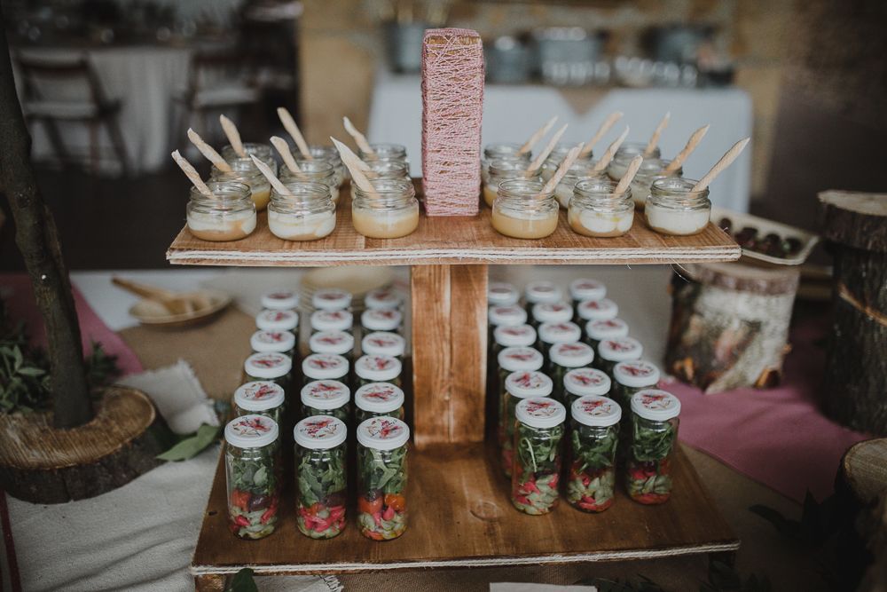 Wedding dessert display featuring tiered wooden stands with mason jars and sweet treats.