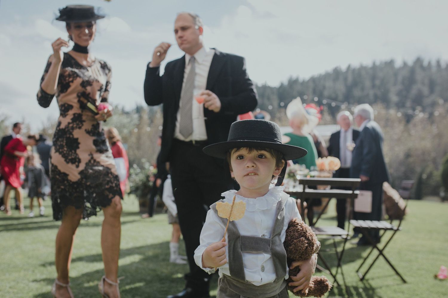 Outdoor wedding guests enjoying refreshments on a sunny lawn.