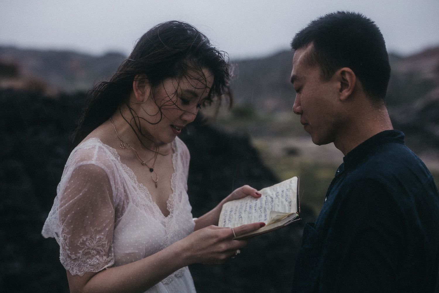A couple reads from a handwritten letter together in a mountainous setting.