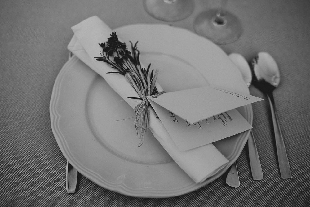 Black and white detail of place setting with delicate floral sprig tied to napkin.