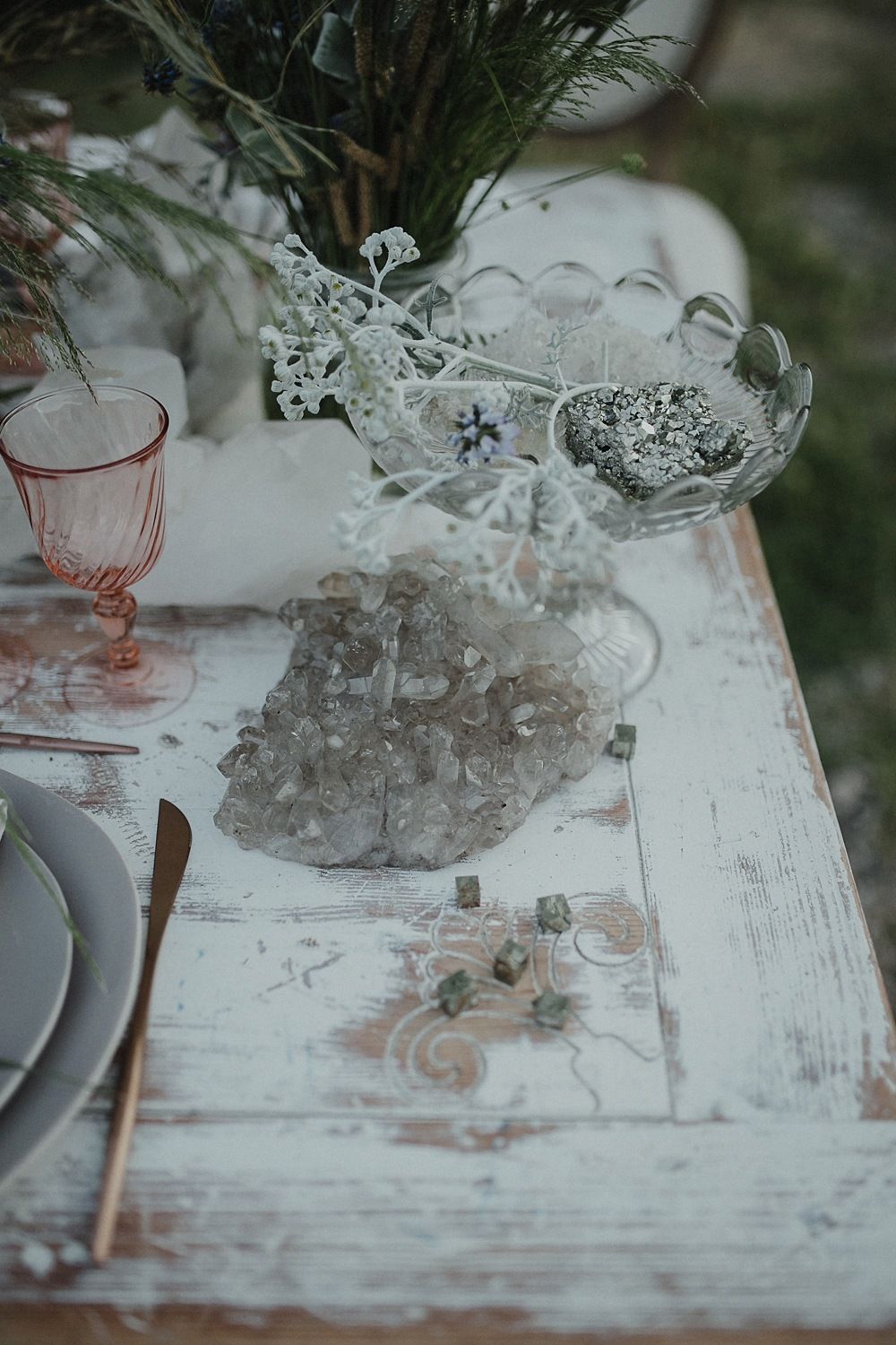 Vintage crystal glassware and pink glasses on a weathered white wooden table.