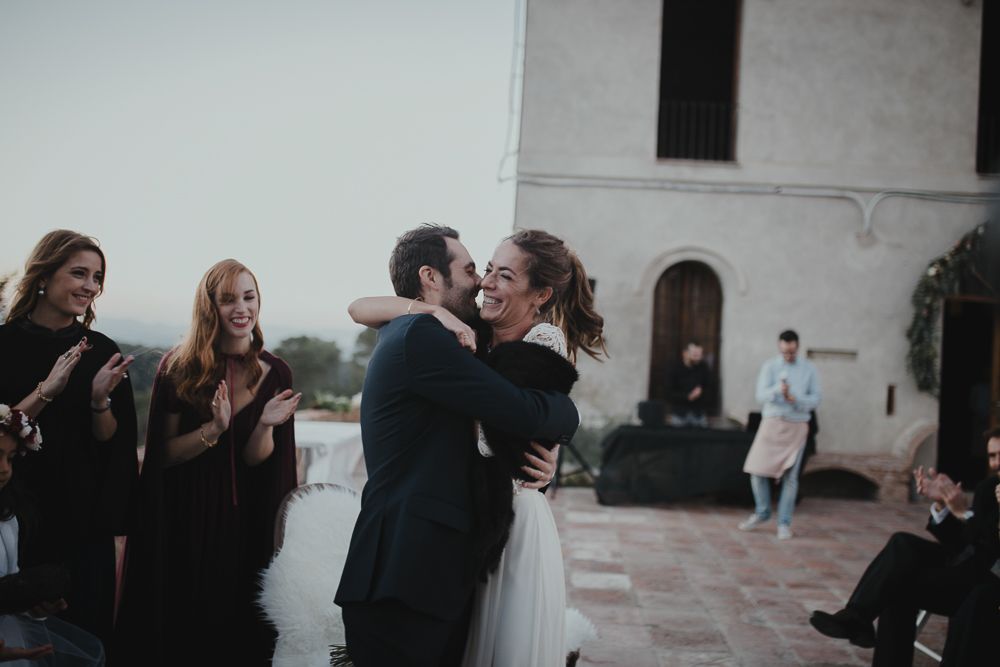 Wedding guests clap and celebrate during a joyous outdoor ceremony moment.
