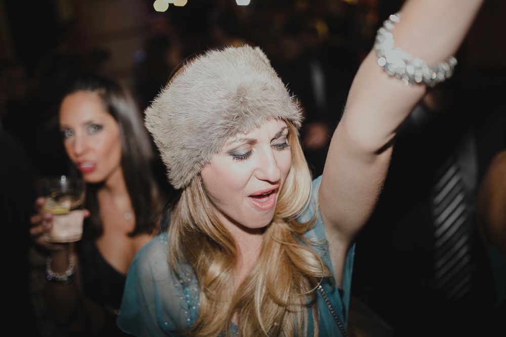 Energetic party guest celebrates with enthusiastic gesture in dark reception venue.