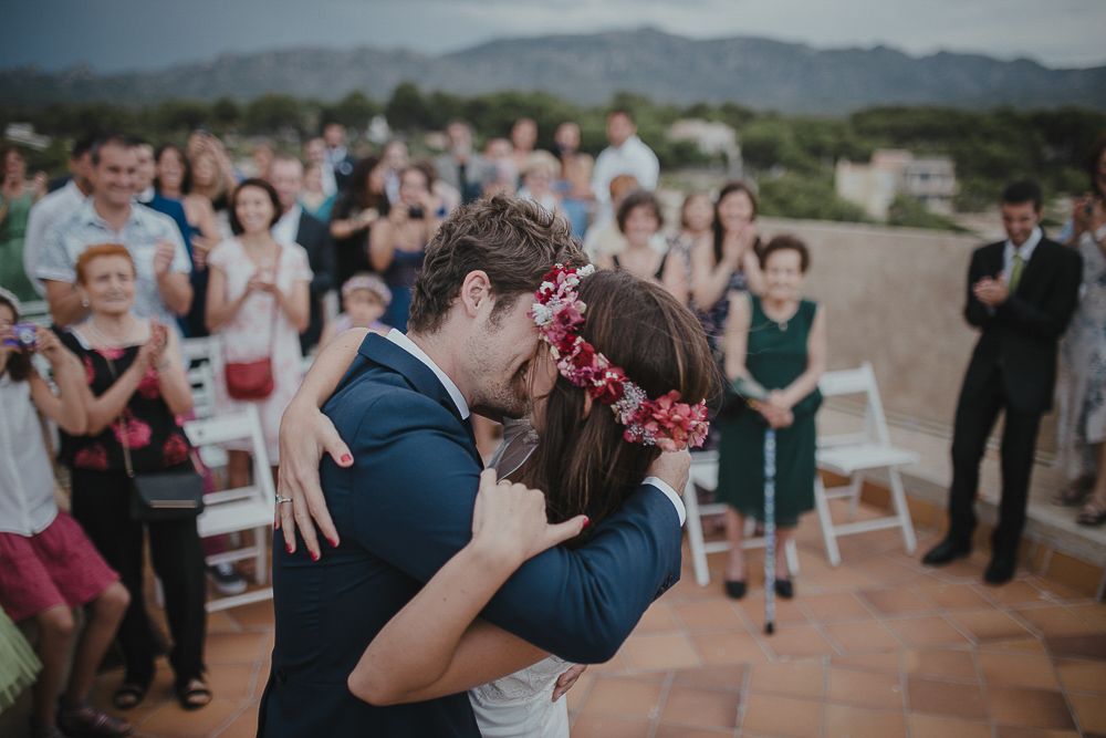 Newlyweds share their first dance surrounded by applauding guests on an outdoor terrace.