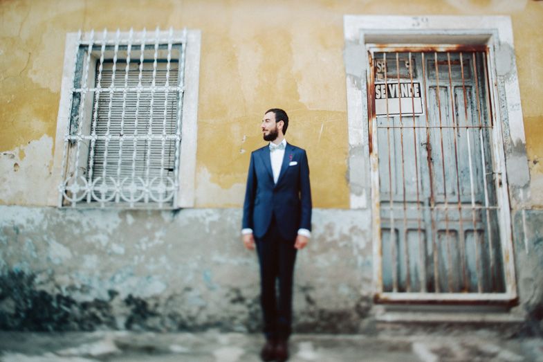 Close-up view of person against aged yellow wall with metal window bars and wooden door.