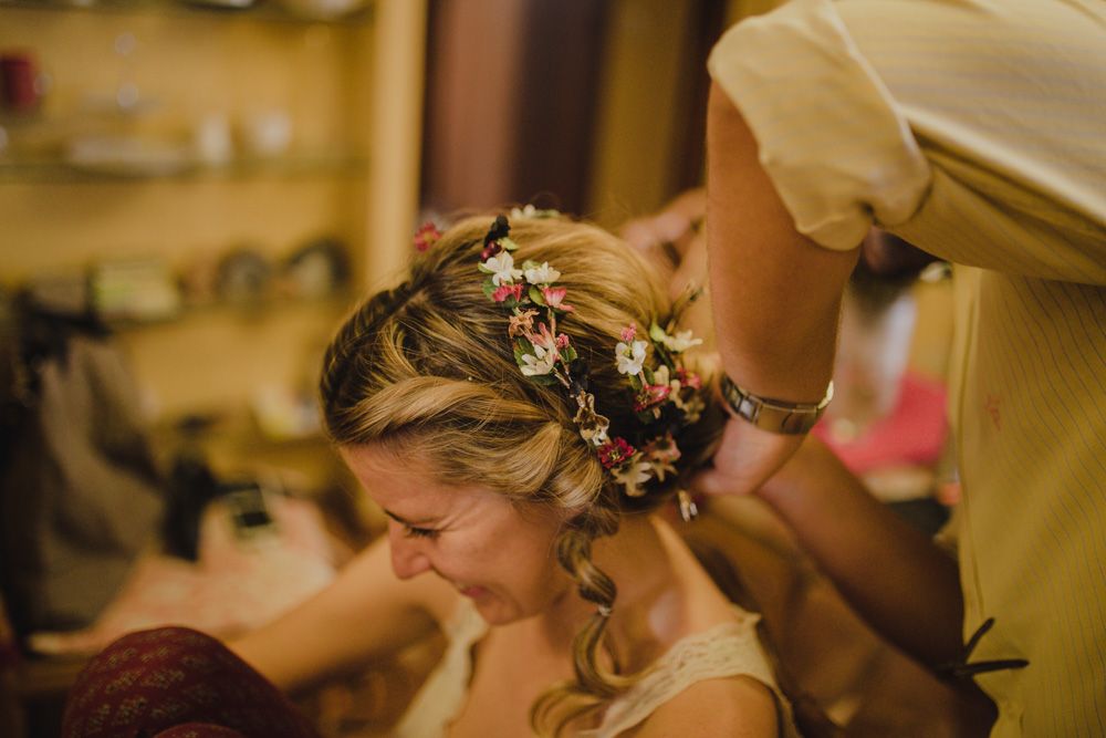 Detailed shot of wedding hair preparation with delicate flowers woven into braids.