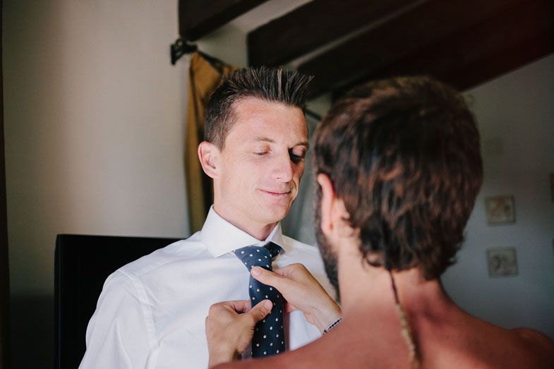 Close up of someone adjusting a blue necktie and white dress shirt.