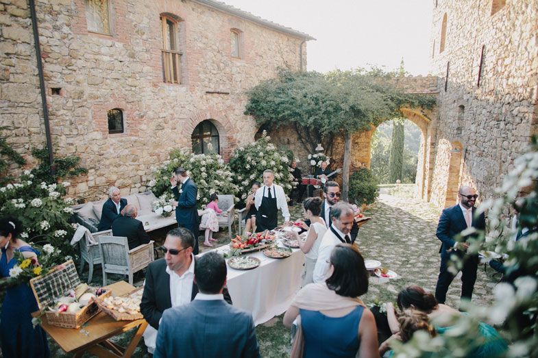 Outdoor wedding reception at a rustic stone villa with tables and decorations.