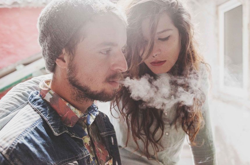 Couple sharing an intimate moment with vapor smoke in soft natural lighting.