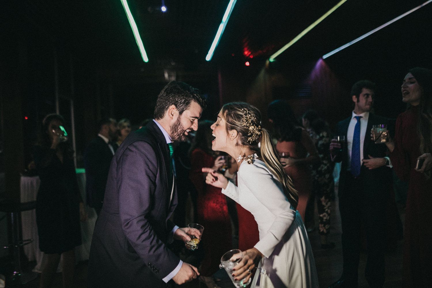 A lively wedding dance moment captured on the dance floor with colorful lighting effects.