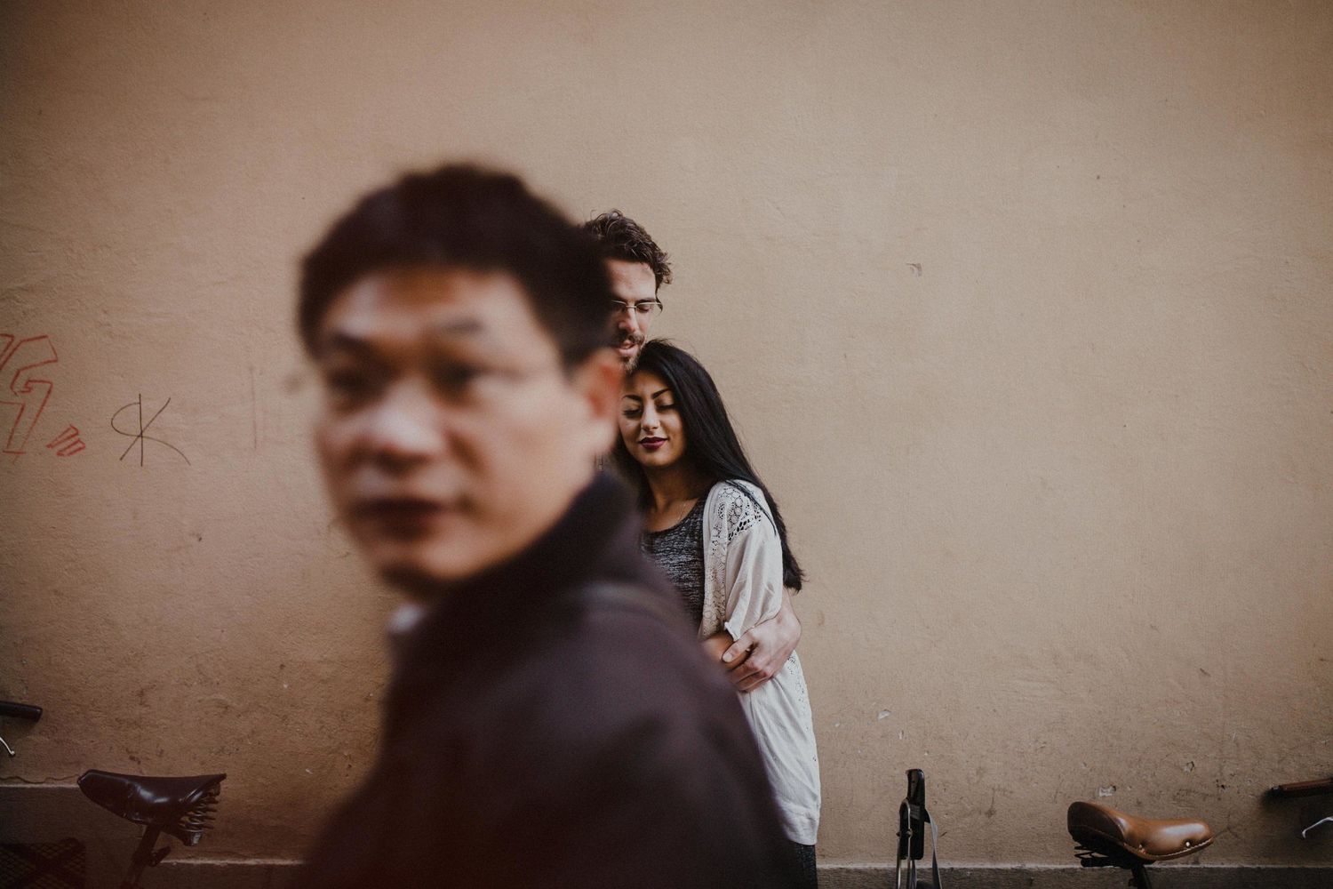 Artistic portrait with selective focus showing figures against a beige wall.