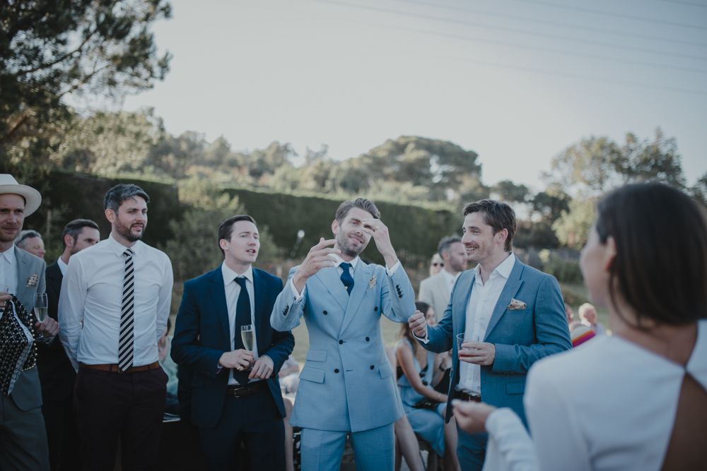 Guests mingling and socializing at an outdoor event with trees in the background.