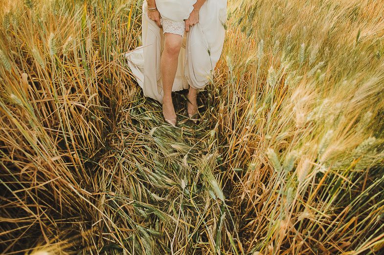 Close up view of dress flowing through tall golden wheat field.