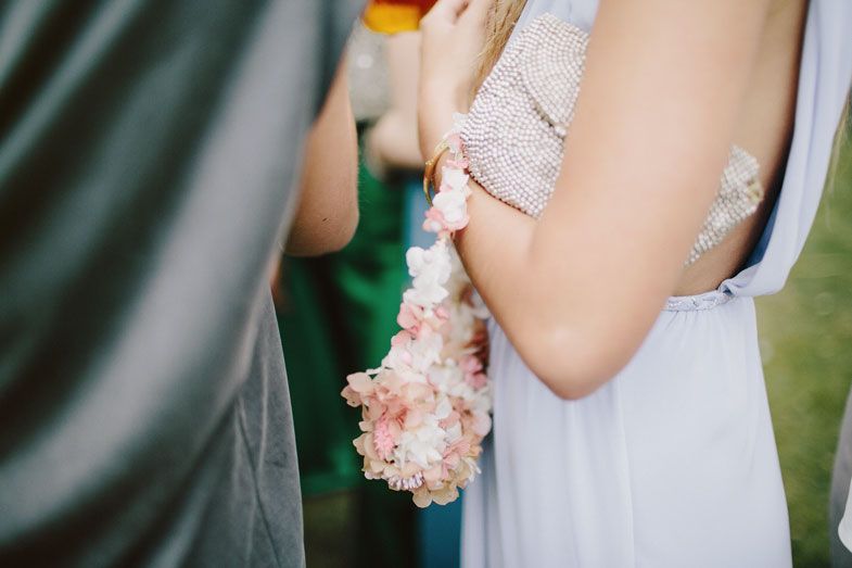 Delicate pink corsage on a white dress sleeve at a wedding.