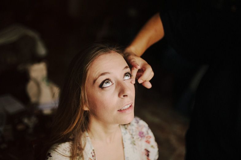 Close-up beauty shot during bridal preparation in dramatic lighting.