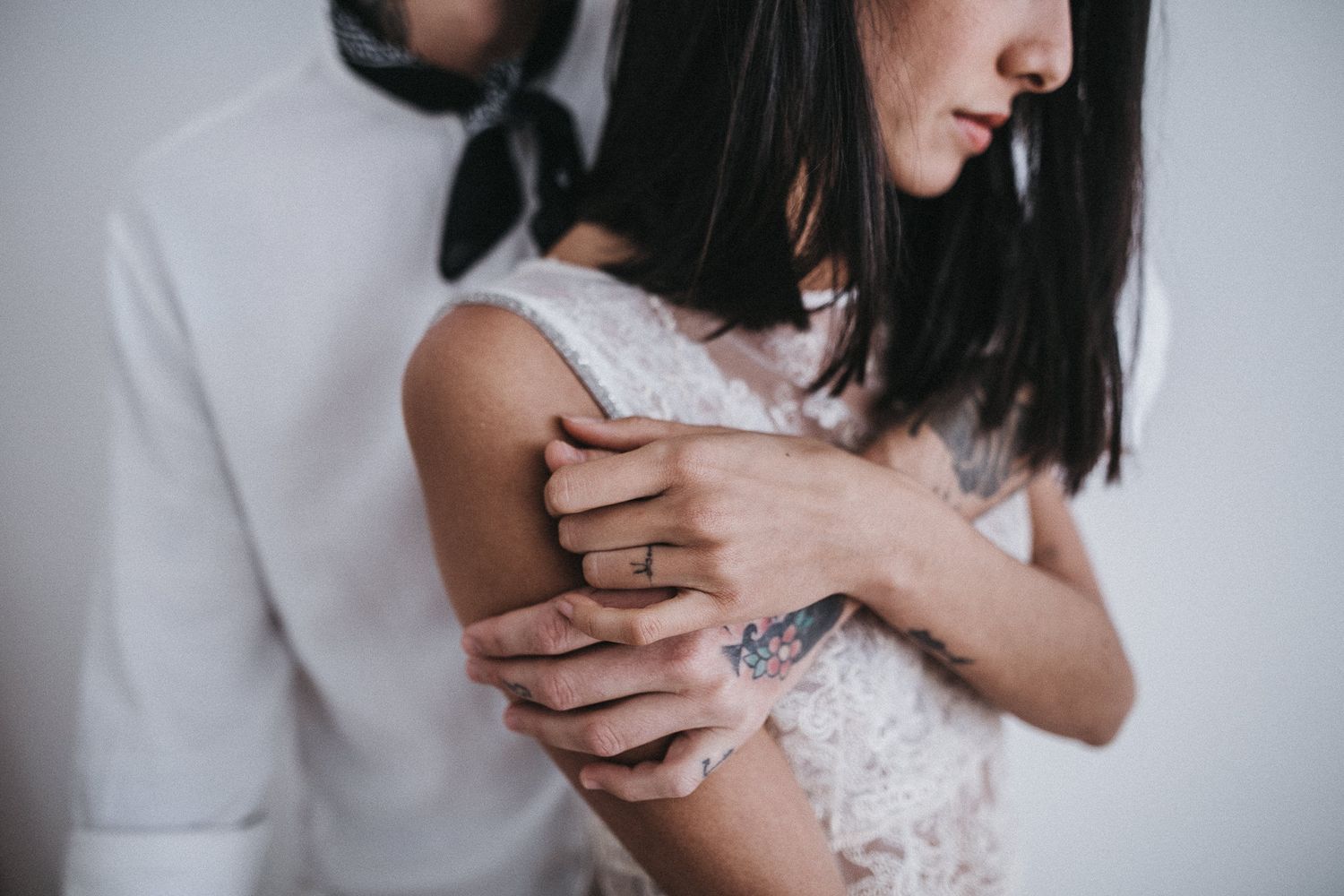 An intimate moment captured between a couple in white lace and formal wear.