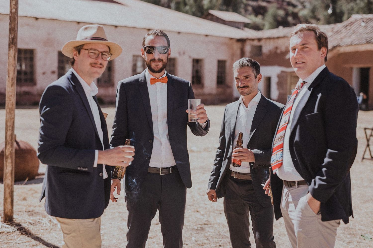A group of guests in formal attire having animated conversation at an outdoor event.