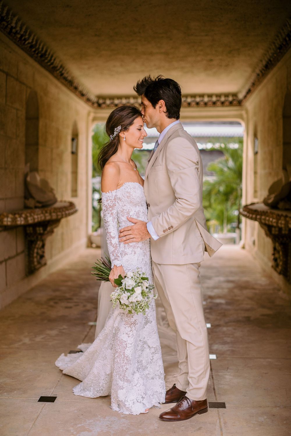 Romantic wedding moment in a covered stone archway corridor.