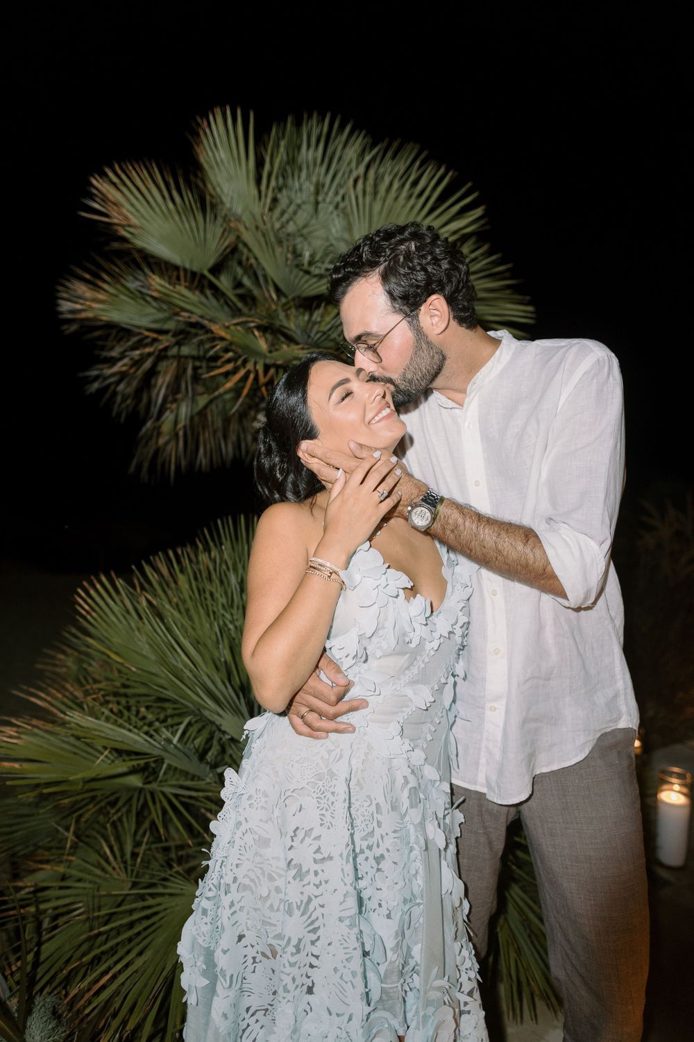 Romantic evening dance under palm trees with soft lighting.