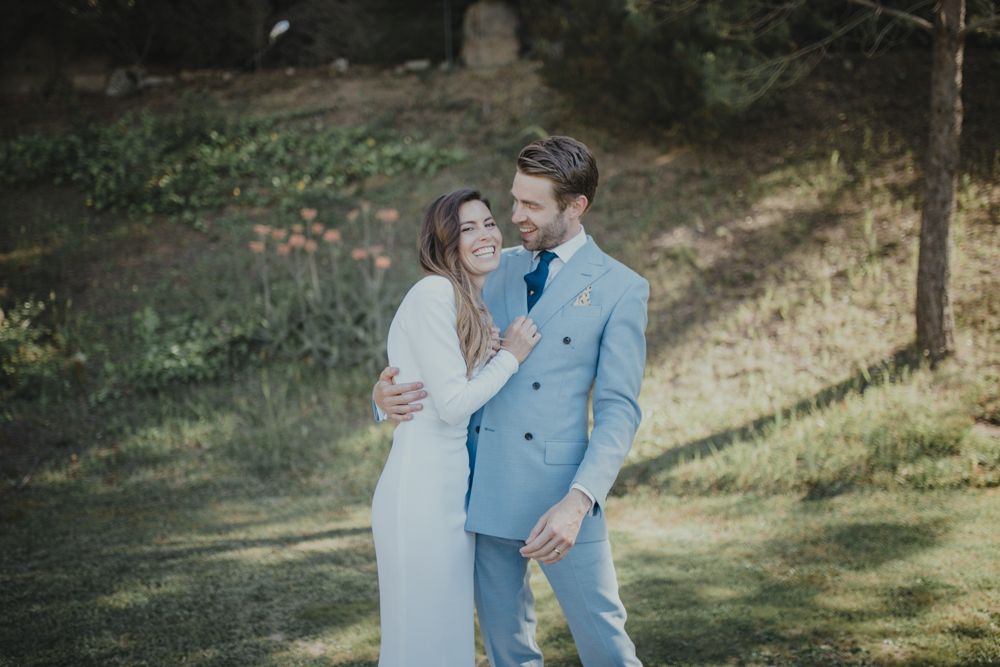 Couple sharing an intimate moment together outdoors wearing light blue suit and white dress.