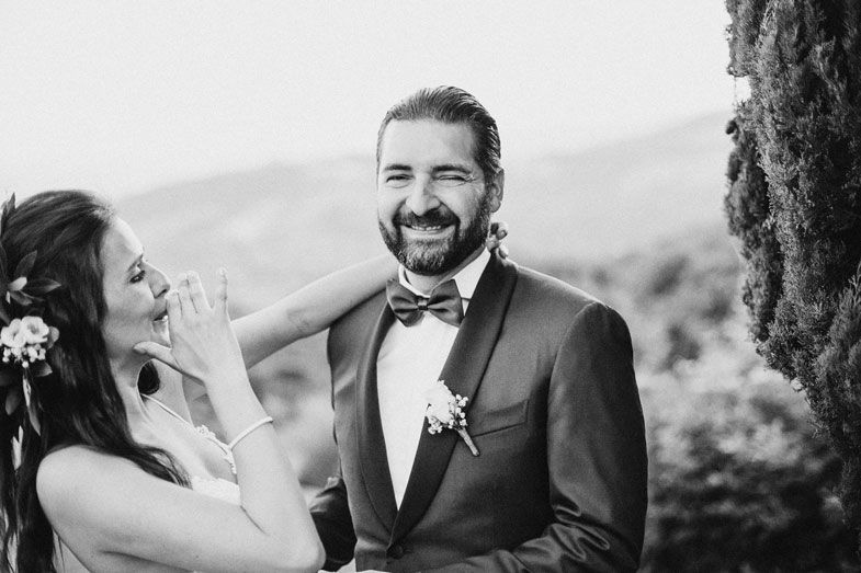 A wedding couple shares a joyful candid moment against a mountain backdrop.