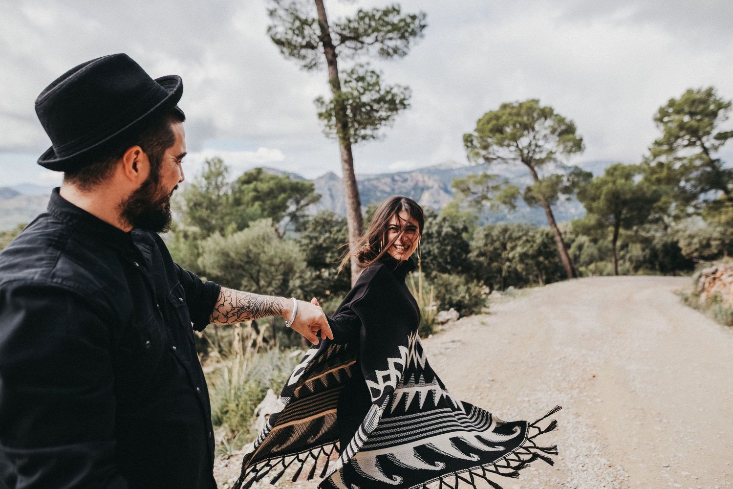 A couple sharing a playful moment on a winding mountain path.