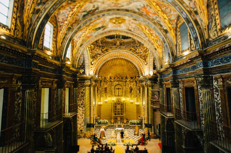 Ornate baroque church interior with golden details and vaulted ceiling.
