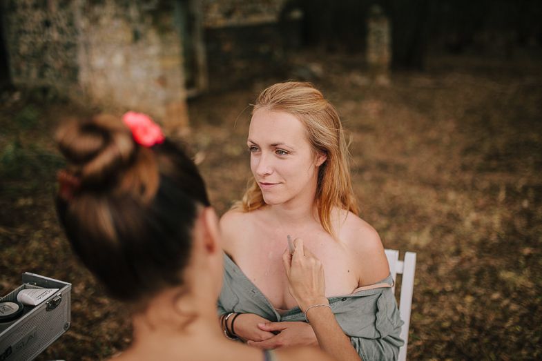 A behind-the-scenes makeup session taking place outdoors on a sunny autumn day.