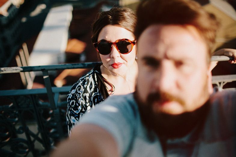 Two passengers inside a car on a sunny day, with one wearing sunglasses.