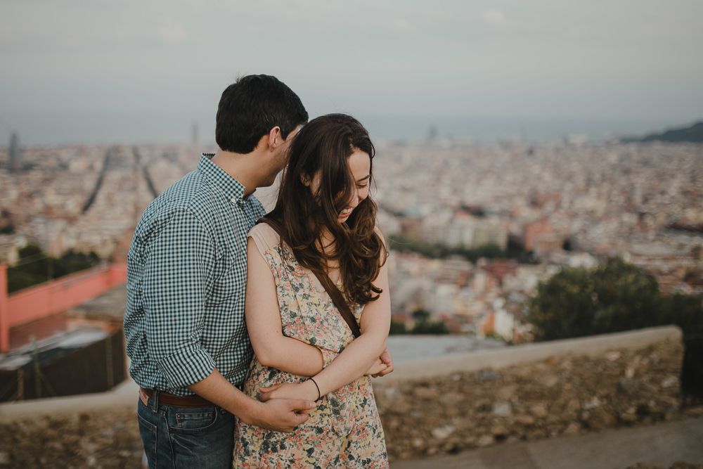 Romantic couple embracing while overlooking a scenic cityscape at sunset.