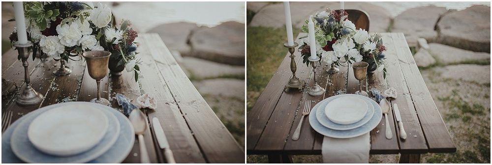 Rustic table setting with white floral arrangements and place settings on weathered wood.