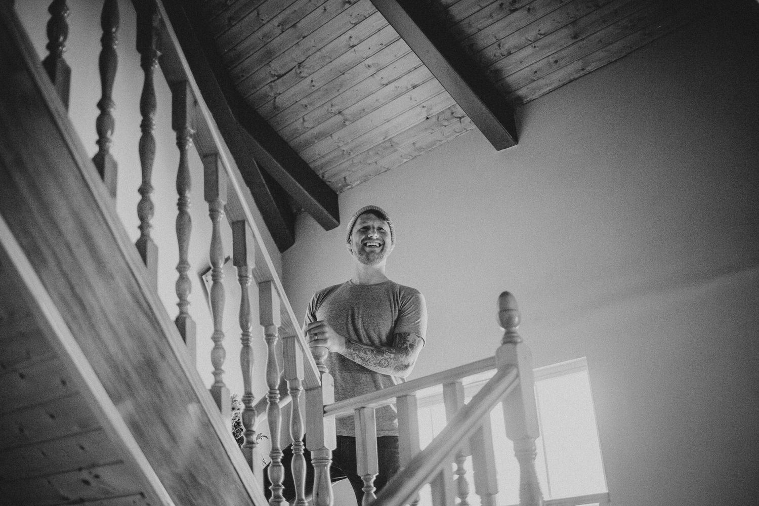 Black and white interior shot of wooden staircase with dramatic natural lighting.