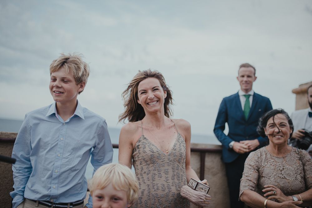 Wedding guests smile and laugh during an outdoor celebration.