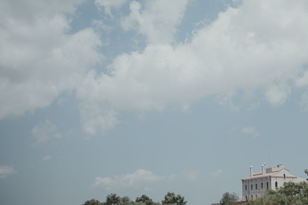 White building visible in the distance under a cloudy blue summer sky.