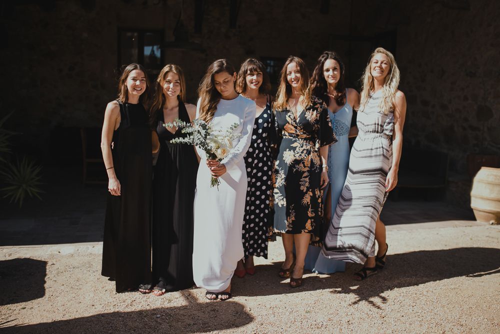 A group poses together at a wedding celebration in mixed formal attire.