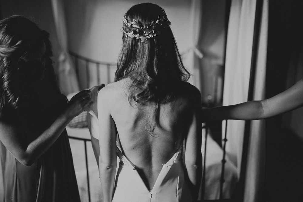 Dramatic black and white photo showing the back detail of a wedding dress and floral crown.