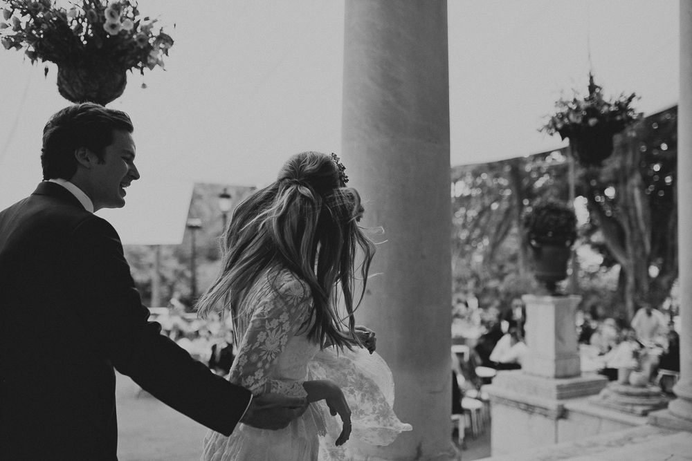 Black and white candid wedding photo showing joyful laughter near classical columns.