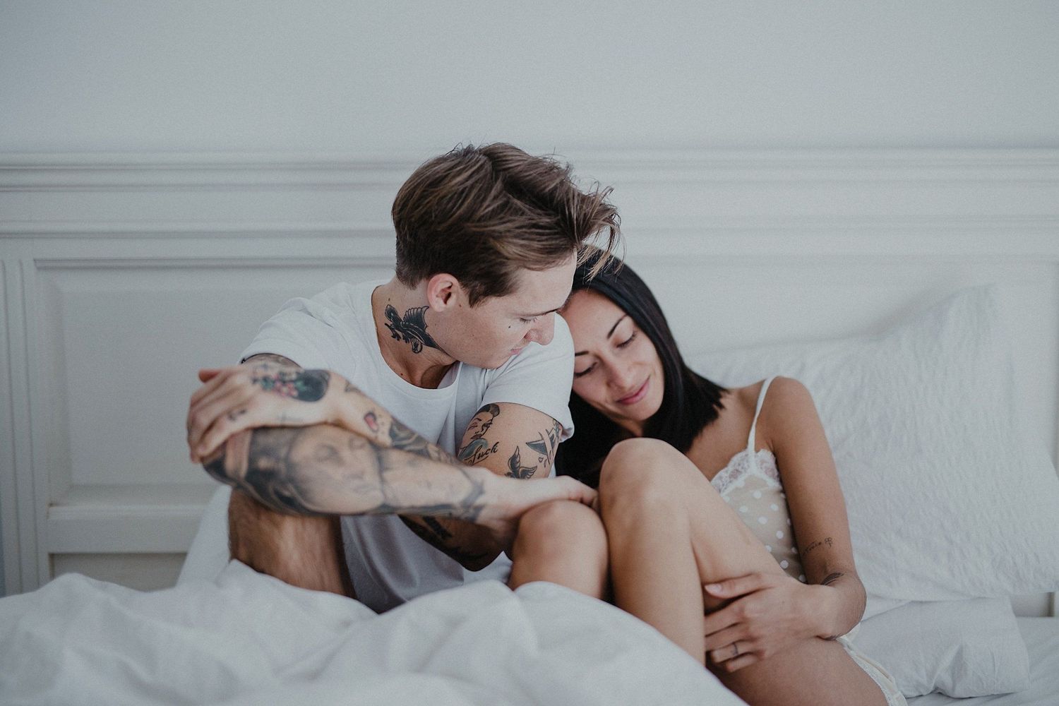 Couple sharing intimate moment on white bed.