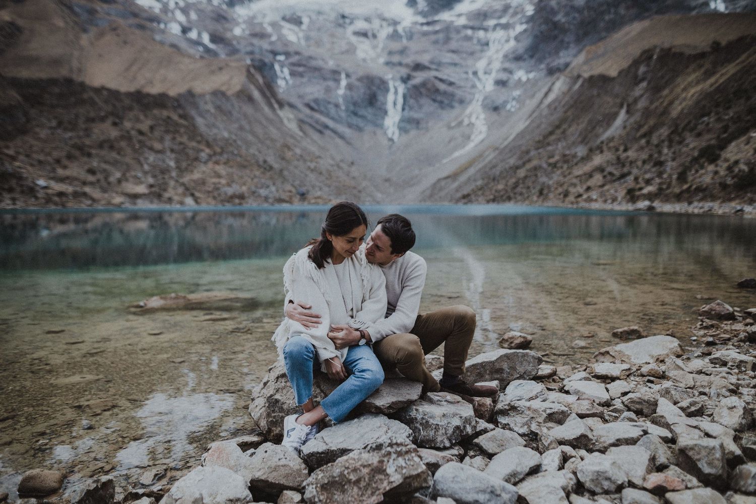 A romantic moment captured by a turquoise alpine lake with snow-capped mountains in the background.