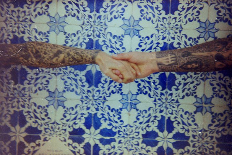 Close-up of hands joining together against blue and white patterned background.